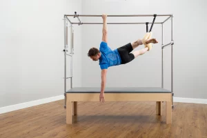 hombre colgándose por la mesa trapeze table de parte de la formación de Pilates Trapeze Table de Balanced Body
